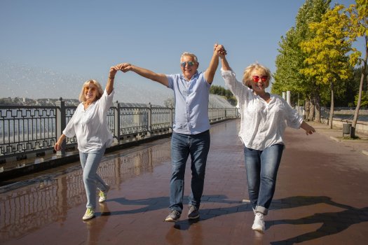 Eine Brücke. Ein Mann in der Mitte. 2 Frauen je links und rechts, Jeans, weiße Blusen halten einander an den Händen.